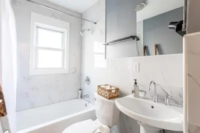 a white bathroom with a sink and a toilet at The B&W Haven 5BR Home with yard theater in Bridgeport