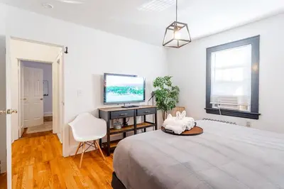 a bedroom with a bed and a desk and a television at The B&W Haven 5BR Home with yard theater in Bridgeport
