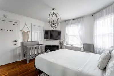 a bedroom with a bed and a crib and a chandelier at Modern 3BR Apartment Downtown HarborPt I-95 Train in Stamford