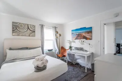 a white bedroom with a bed and a desk at Modern 3BR Apartment Downtown HarborPt I-95 Train in Stamford