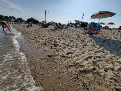 a group of people on a sandy beach with umbrellas at Stamford Bohemian by HarborPoint Downtown &Train in Stamford