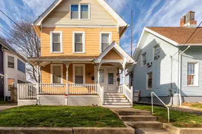 a yellow and white house with a porch at Charming 2BR Getaway with Modern Comforts in Bridgeport