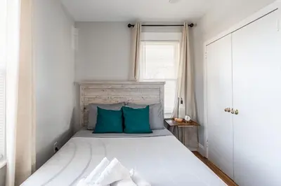 a bedroom with a bed with blue pillows and a window at Sunny & Spacious 2BD 1BA WFH Apt-Huge Yard & Patio in Fairfield