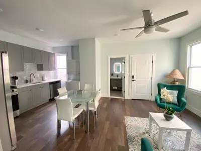 a kitchen and living room with a glass table and chairs at MetLife Stadium Apartments Near NYC in Jersey City