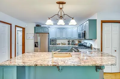 a kitchen with blue cabinets and a marble counter top at Charming Ballston Spa Home with Sauna and Private Pool in Ballston Spa