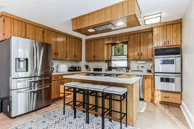 a kitchen with wooden cabinets and a stainless steel refrigerator at Enchanting Historic Home near West Point Beacon in Cornwall-on-Hudson