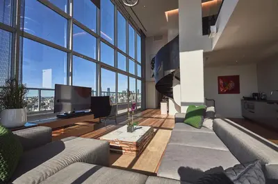 a living room with a couch and a tv and large windows at Hotel Indigo Lower East Side New York by IHG in New York