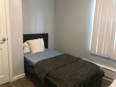 a small bedroom with a bed with a pillow at 30 mins to TIMES SQ!!!! in Corona
