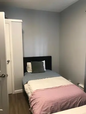 a small bedroom with a bed with a black headboard at 30 mins to TIMES SQ!!!! in Corona