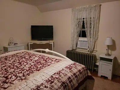 a bedroom with a bed and a tv and a window at On the Water Spacious Comfortable Historic House in West Haven