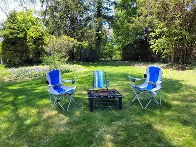 a group of three chairs and a table in the grass at On the Water Spacious Comfortable Historic House in West Haven