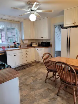 a kitchen with a table and a refrigerator at On the Water Spacious Comfortable Historic House in West Haven