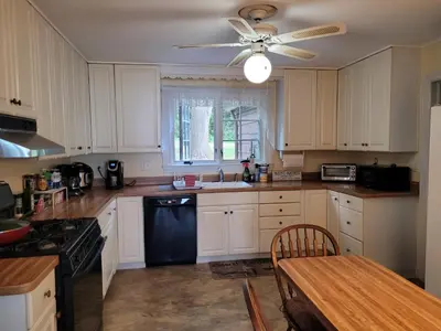 a kitchen with white cabinets and a ceiling fan at On the Water Spacious Comfortable Historic House in West Haven