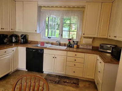 a kitchen with white cabinets and a sink and a window at On the Water Spacious Comfortable Historic House in West Haven