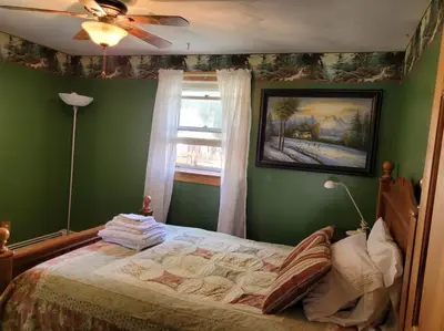 a bedroom with a bed with green walls and a window at Lake Congamond Suffield House in Granby