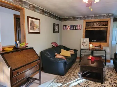 a living room with a black leather couch and a tv at Lake Congamond Suffield House in Granby