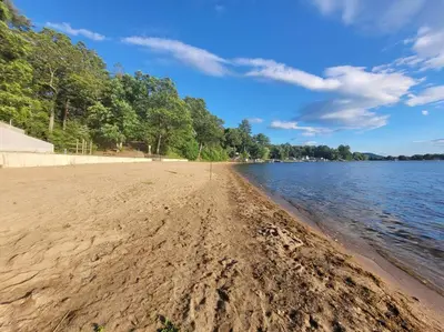 a sandy beach next to a body of water at Lake Congamond Suffield House in Granby