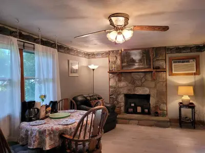 a living room with a table and a stone fireplace at Lake Congamond Suffield House in Granby