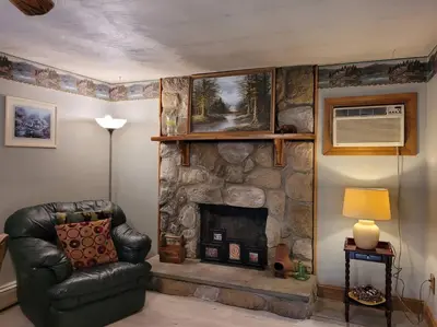 a living room with a stone fireplace and a leather chair at Lake Congamond Suffield House in Granby