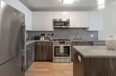 a kitchen with white cabinets and a stainless steel refrigerator at Luxury Apt with Pool in Stamford