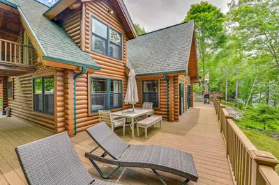 a cabin with a deck with chairs and a table at Lakefront Corinth Log Home Private Dock, Fire Pit in Lake Luzerne