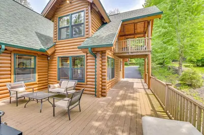 a cabin with a deck with a table and chairs at Lakefront Corinth Log Home Private Dock, Fire Pit in Lake Luzerne