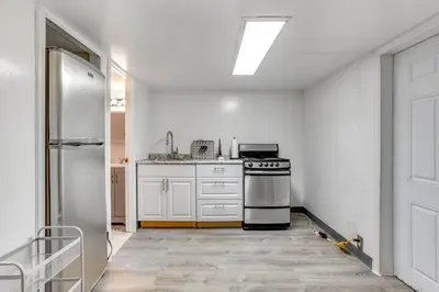 a white kitchen with a stove and a refrigerator at Convenient Apt 2 Mi to Sprain Ridge Park! in Yonkers