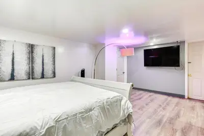 a bedroom with a white bed and a flat screen tv at Convenient Apt 2 Mi to Sprain Ridge Park! in Yonkers