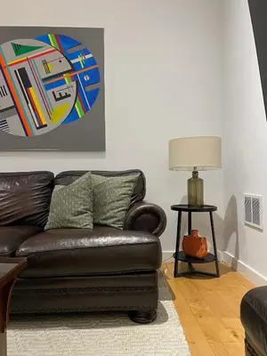 a living room with a brown leather couch and a lamp at Urban Peak Escape in Lenox