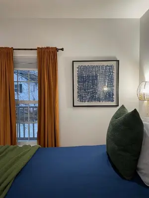 a bedroom with a blue bed and a window at Urban Peak Escape in Lenox