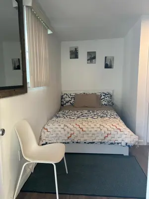 a small bedroom with a bed and a chair at Cozy apt 30mins from Times square!!! in Corona