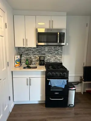 a kitchen with a black stove and a microwave at Cozy apt 30mins from Times square!!! in Corona