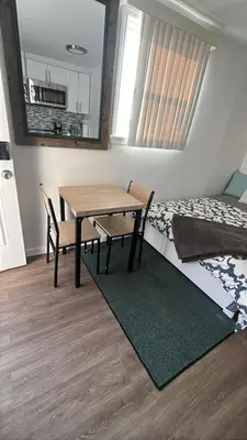 a room with a table and chairs and a bed at Cozy apt 30mins from Times square!!! in Corona