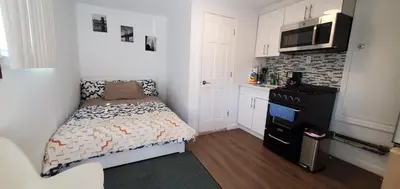 a small bedroom with a small bed and a kitchen at Cozy apt 30mins from Times square!!! in Corona