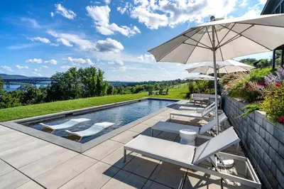 a swimming pool with chairs and an umbrella at Hudson House in Newburgh