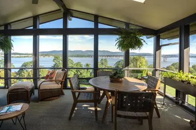 a room with a table and chairs and a view of the water at Hudson House in Newburgh