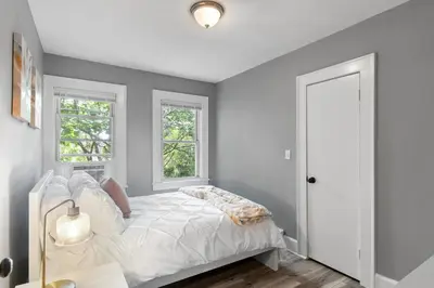 a white bedroom with a bed and two windows at Centrally Located Stamford Gem in Stamford