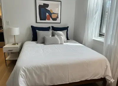 a white bed with blue pillows in a bedroom at Chill In The Village in New York