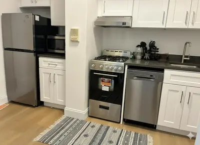 a kitchen with a stainless steel stove and white cabinets at Chill In The Village in New York
