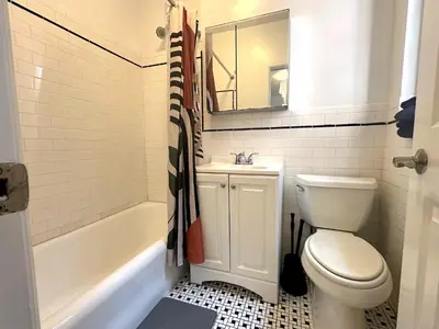 a bathroom with a white toilet and a sink at West Village Lush Green in New York