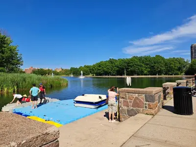 a group of people standing around a boat in the water at Oasis in New Jersey - 2BR NYC Access in West New York