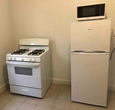 a white stove and refrigerator with a microwave on top of it at Spacious and bright 2-bedroom apartment with 1-bathroom and private street entrance, MetLife Stadium FIFA World Cup 25 minutes away in Paterson