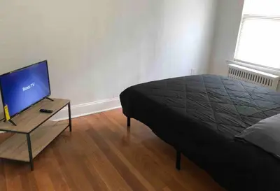a bedroom with a bed and a table with a television at Spacious 2-bedroom apartment with 1-bathroom and private street entrance, MetLife Stadium FIFA World Cup 25 minutes away in Paterson