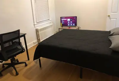 a bedroom with a bed and a chair and a television at Spacious 2-bedroom apartment with 1-bathroom and private street entrance, MetLife Stadium FIFA World Cup 25 minutes away in Paterson