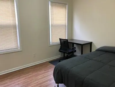 a bedroom with a desk and a bed and two windows at Large and private 3 bedroom and 1 bathroom apartment near Newark International Airport EWR and New York City, MetLife Stadium FIFA World Cup 20 minutes away in Newark