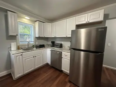 a kitchen with white cabinets and a stainless steel refrigerator at Strikeout All Star Baseball Rentals in Oneonta