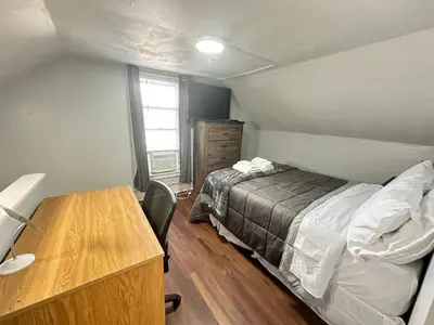 a bedroom with a bed and a wooden desk at Strikeout All Star Baseball Rentals in Oneonta