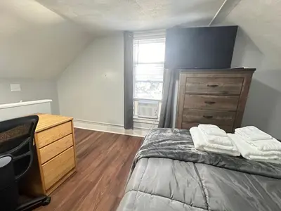 a bedroom with a bed and a dresser and a window at Strikeout All Star Baseball Rentals in Oneonta