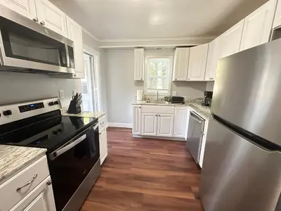 a kitchen with white cabinets and a stainless steel refrigerator at Strikeout All Star Baseball Rentals in Oneonta