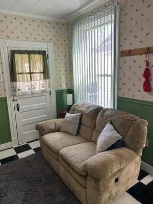 a living room with a brown couch and a window at Adirondack Spirit in Gloversville